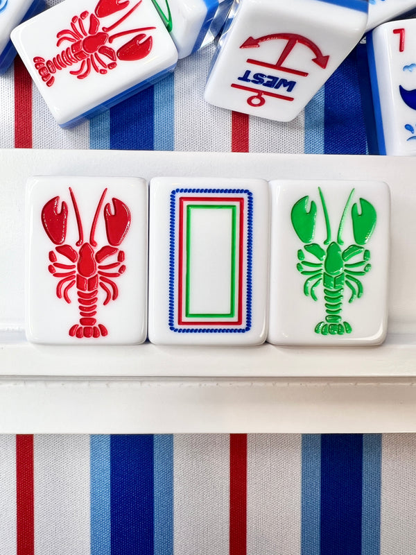 Close-up of Mahjong tiles with lobster and anchor designs on a striped background